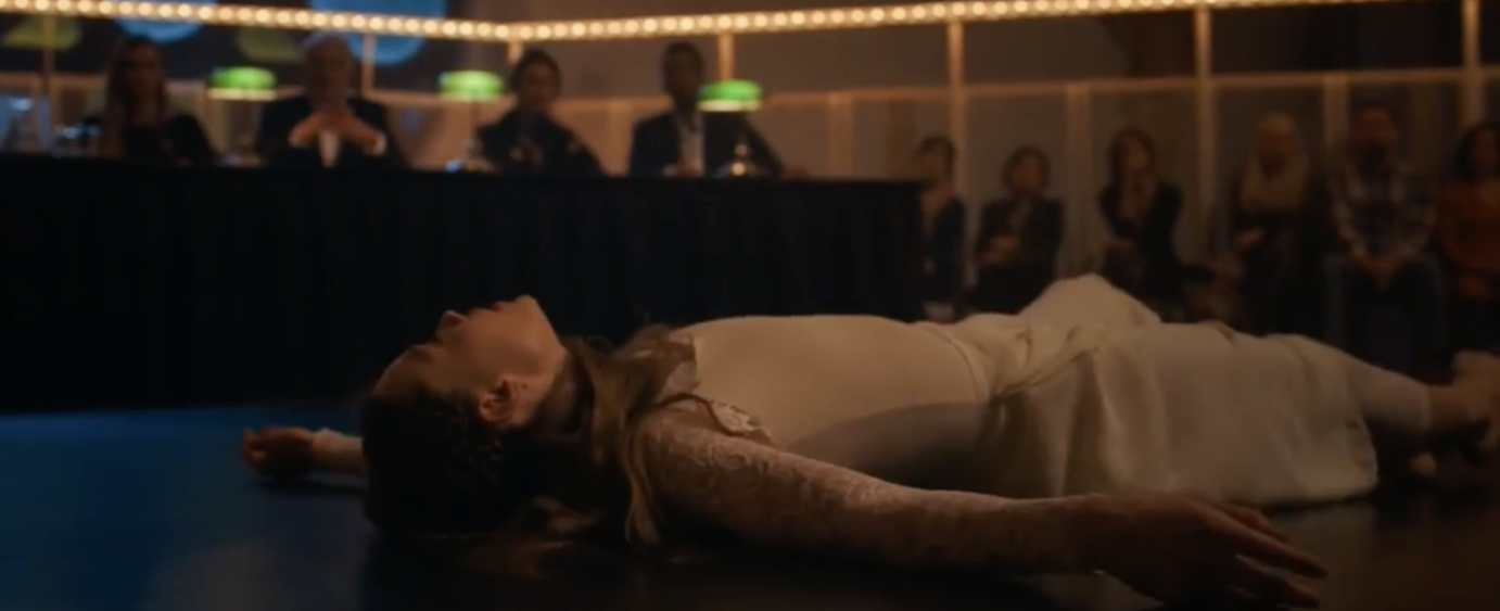 In a long-sleeved white dress, Marine lies on the floor, her arms akimbo, as the judges look on, surprised