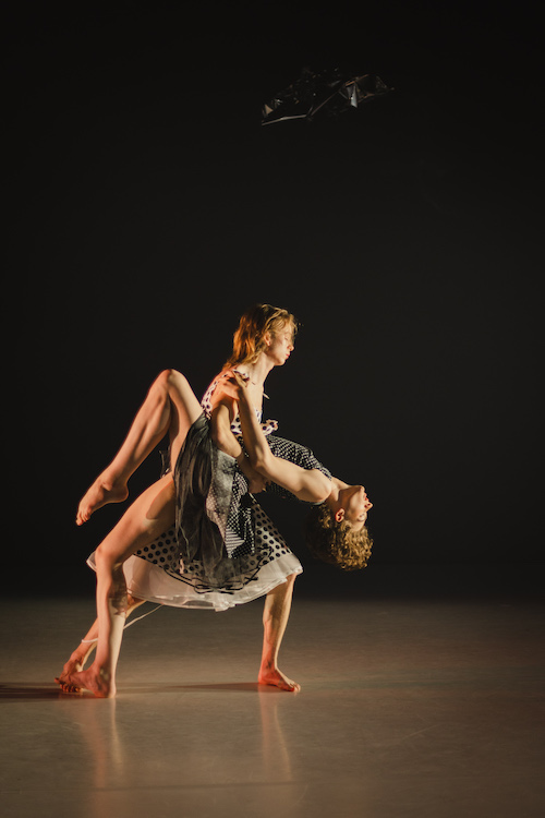 a couple wearing whit and black patterend outfits embrace in a dance duet