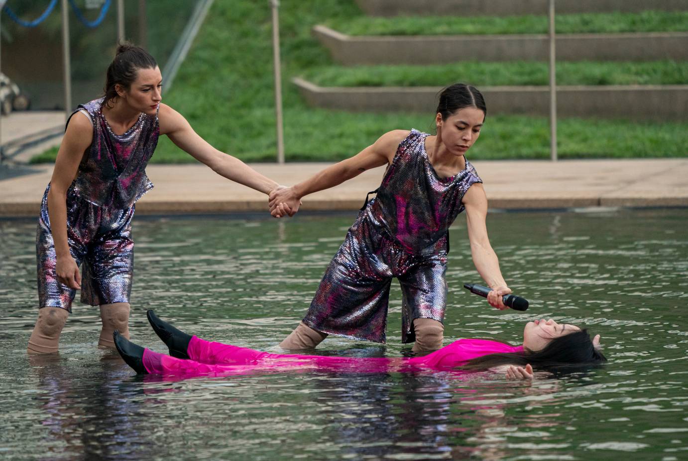 Jen Surigat lies in the pool, her black hair and fuchsia dress streaming around her as two dancers offer assistance.