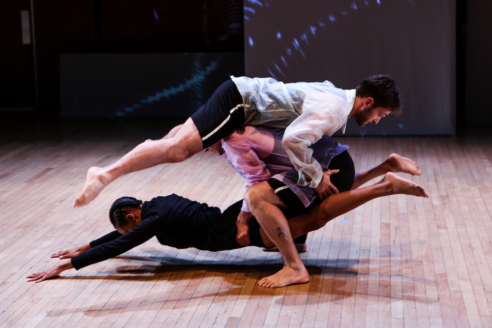 an unusual balance of three people who seem suspended in space. Actually they are carrying on another in an intricate shape.